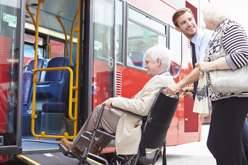 Driver Helping Senior Couple Board Bus Via Wheelchair Ramp